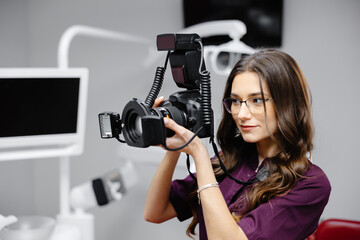 Portrait of female dentist holding photo camera in hands, standing in dental office