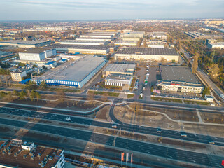 Aerial view of goods warehouse. Logistics center in industrial city zone from above. Aerial view of trucks loading at logistic center. View from drone.