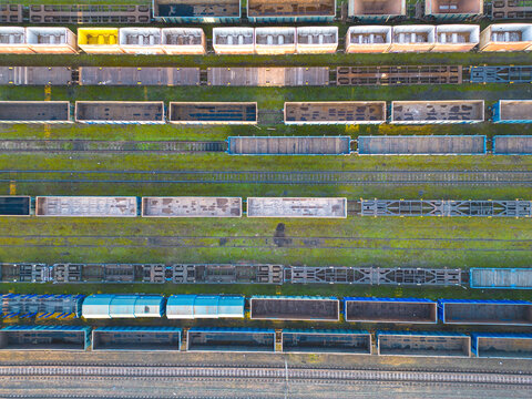 Cargo trains close-up. Aerial view of colorful freight trains on the railway station. Wagons with goods on railroad. Heavy industry. Industrial conceptual scene with trains. Top view from flying drone