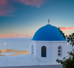 Fototapeta na wymiar Classical Greek church architecture. Sunset view of the white church with blue domes. Important travel destinations in Greece. Santorini island.