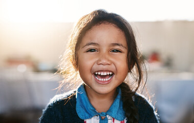 Happy kid, face and girl laughing in living room, playing and having fun in her home. Child,...