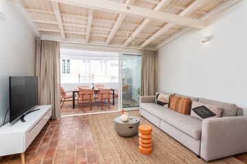 Modern minimalist living room with wooden ceilings and balcony view. Decorative figurines on the table.