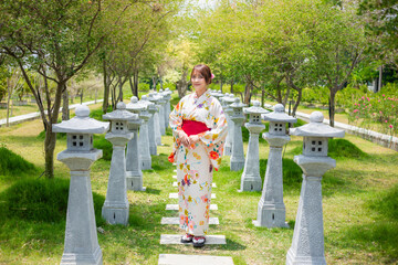 Young woman wearing a Japanese traditional kimono or yukata stand in a garden with torii poles.