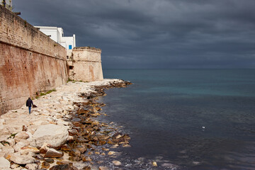 Fototapeta na wymiar Lonely man walking on a rainy day on the seafront of Monopoli in Puglia