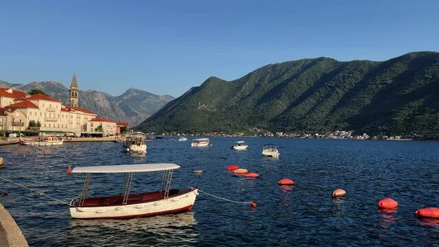 Small boats rock on the sea at the pier near the coast of Perast. Montenegro