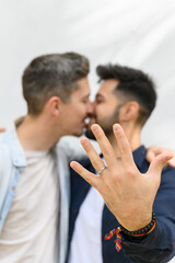 Ethnic guy demonstrating ring and embracing boyfriend after proposal