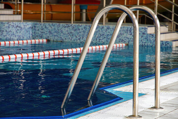 Naklejka premium Handrails and steps for safe descent into the pool.
