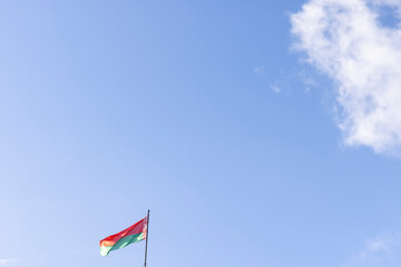 the flag of the Republic of Belarus on a blue sky background with clouds in windy weather
