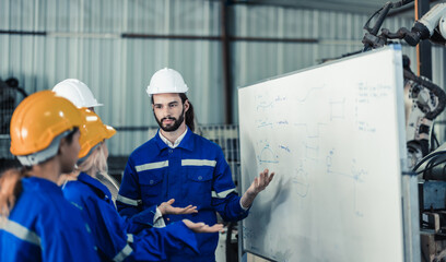 A group of robotic engineers collaboratively brainstorms and discusses ideas with cross-functional teams on a whiteboard to create strategies and solutions to make the working process more efficient.