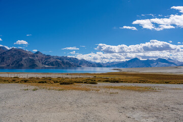 Grass fields in the valley, mountains around the lake and blue sky