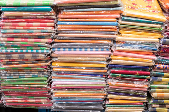 Huge selection of multi-colored tablecloths, curtains, fabric cuts with various patterns lies of trading place.