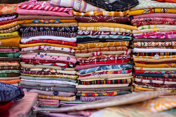 Huge selection of multicolored scarves, pareos, shawls, fabric cuts with various patterns lies of trading place . 