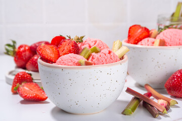 Rhubarb and strawberry ice cream, homemade sorbet gelato, frozen fruity dessert with fresh rhubarb and strawberry slices, on white kitchen table copy space