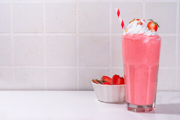 Rhubarb and strawberry milkshake or smoothie, refreshing summer drink, Healthy dieting and antioxidant summer beverage with whipped cream, fresh rhubarb, strawberry slices, on white kitchen table
