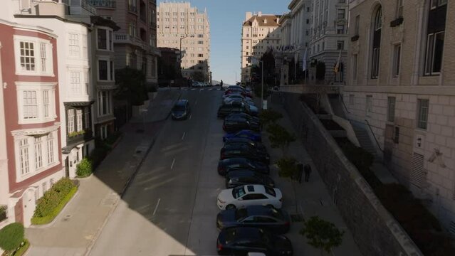 Forwards fly above steep rising street in city. Revealing luxurious hotel building in Nob Hill district. San Francisco, California, USA