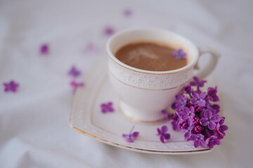 Cup of coffee with lilac flowers on a white background.