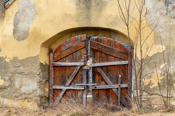 Fototapeta na wymiar Broken wooden gate of an old ruined building. Old ruined gates with brown antique timber gate