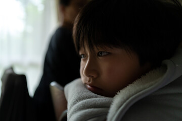 椅子に座って外を眺める日本人の少年