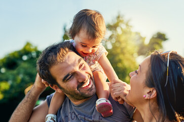 Family, father and daughter on shoulders in park with happy mom, love and summer sunshine. Young...