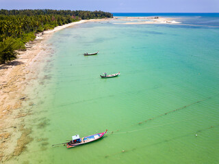 Drone view of longtail boats moored off a tropical sandy beach in Khao Lak, Thailand