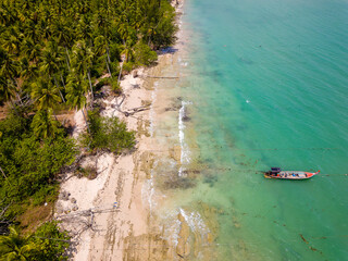 Aerial view of traditional Thai longtail fishin boats moored off a small, palm tree lined tropical beach (Khao Lak, Thailand)