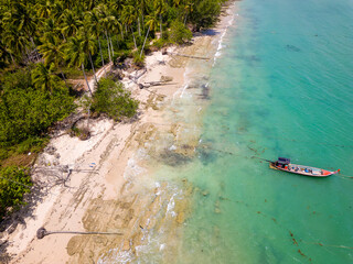 Aerial view of colourful Longtail boats and a tropical beach surrounded by palm trees