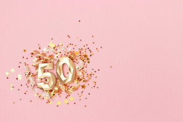 Golden number fifty, ribbons and stars confetti on a pink background. Festive creative concept with...