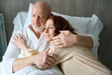 Caring man and woman lying on bed together indoors