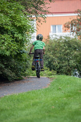 Young kid cycling on a childs bike in a park.