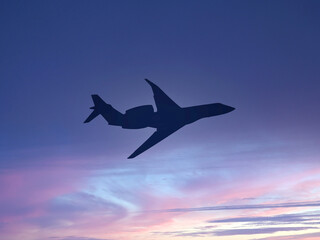 Silhouette of a private executive jet against a dusk sky. Travel concept.