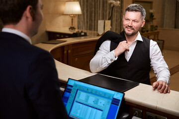 Handsome businessman talking with male receptionist in the hotel