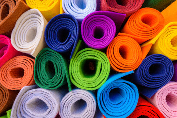 On the street, rolls of felt of different bright colors outside a shop. On the street, rolls of felt of different bright colors outside a shop. Multicolored background of felt rolls.