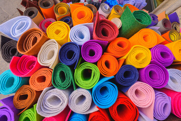 On the street, rolls of felt of different bright colors outside a shop. On the street, rolls of felt of different bright colors outside a shop. Multicolored background of felt rolls.