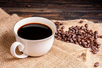 Freshly brewed coffee. Coffee cup or mug arranged on a black wooden table with roasted coffee beans. Espresso mocha cappuccino barista on dark background