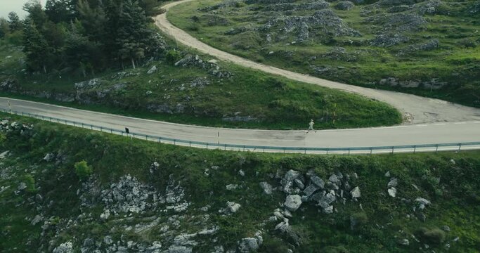 Aerial of a woman running down a mountrain road in Abruzzes Italy