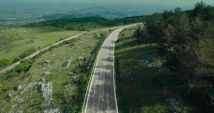 Zenithal aerial of a woman running down a mountain road in Abruzzes Italy