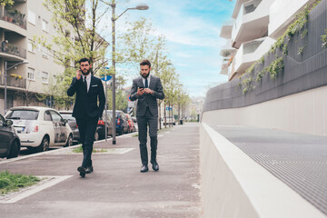 Obraz premium two businessman outdoors using tablet and smartphone