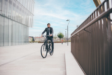 Fototapeta na wymiar Contemporary bearded young stylish businessman going to work by bike