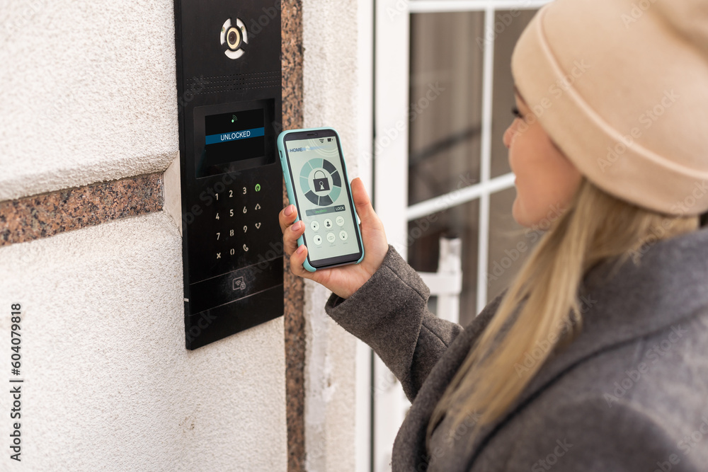 Poster woman locking smartlock on the entrance door using a smart phone. concept of using smart electronic 