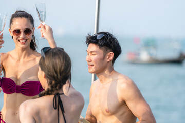 Man and woman friends group enjoy celebration party and fun luxury summer outdoor lifestyle by drinking champagne together, travel vacation on catamaran yacht boat sailing in tropical sea sunset on