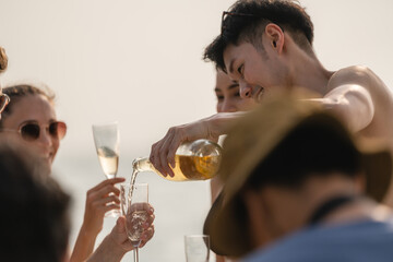 Man and woman friends group enjoy celebration party and fun luxury summer outdoor lifestyle by drinking champagne together, travel vacation on catamaran yacht boat sailing in tropical sea sunset on