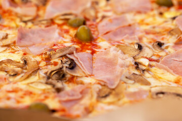 Fresh tasty pizza with bacon, mushrooms and olives close-up. Selective focus, defocus