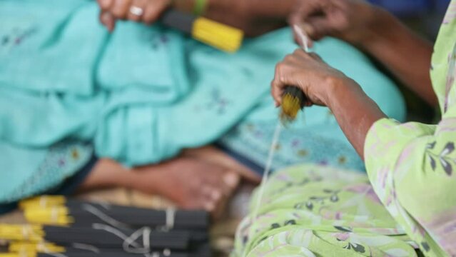 Closeup of a bunch of incense sticks being tied with thread for packing