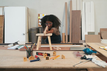 Female carpenter working in wood workshop. Female joiner wearing safety uniform and working in...