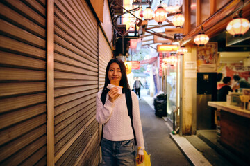 吉祥寺の路地裏の商店街で食べ歩きをする女性