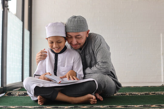 Father and son in mosque praying and reading holly book quran together. Islamic education concept.