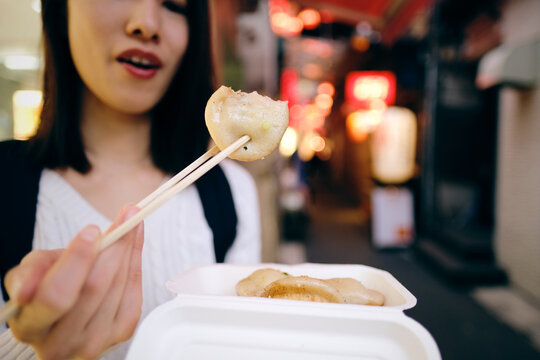 吉祥寺の路地裏の商店街で小籠包を食べる女性