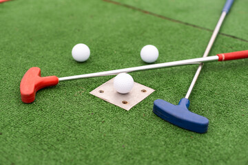 colorful golf putters with golf balls on synthetic grass