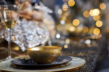 Christmas table setting with plates, silverware, gift box and decorations in black and gold colors