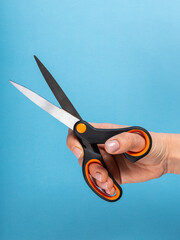 Female hand holds scissors on blue background